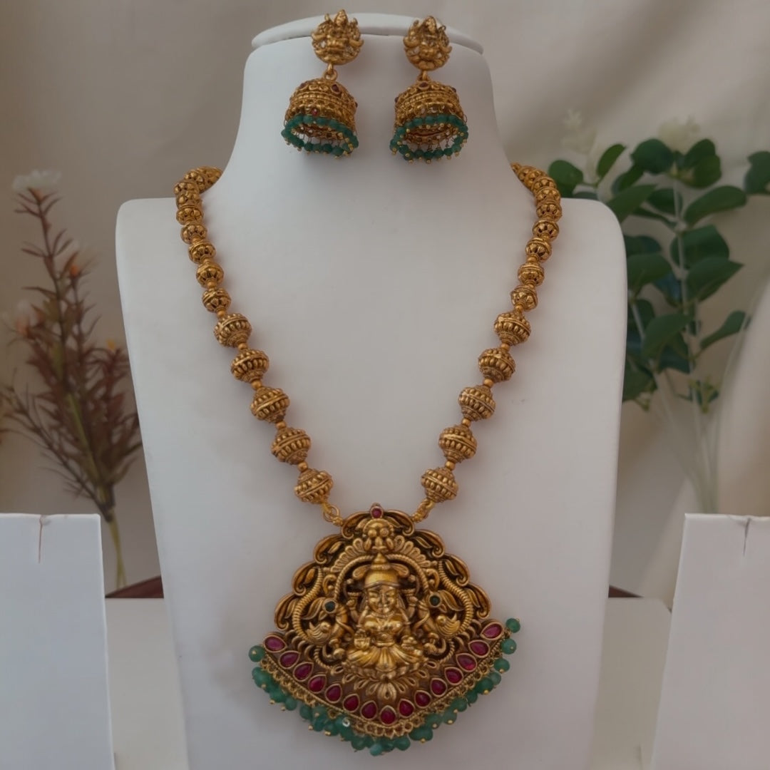 Gold necklace and earrings on a mannequin with a blurred background