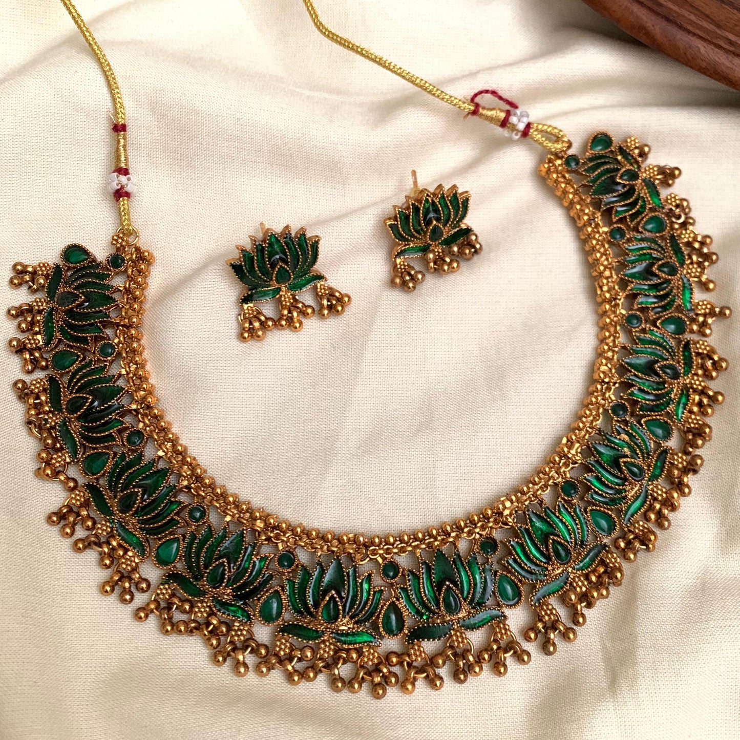 Ornate gold and green necklace set on a white fabric background