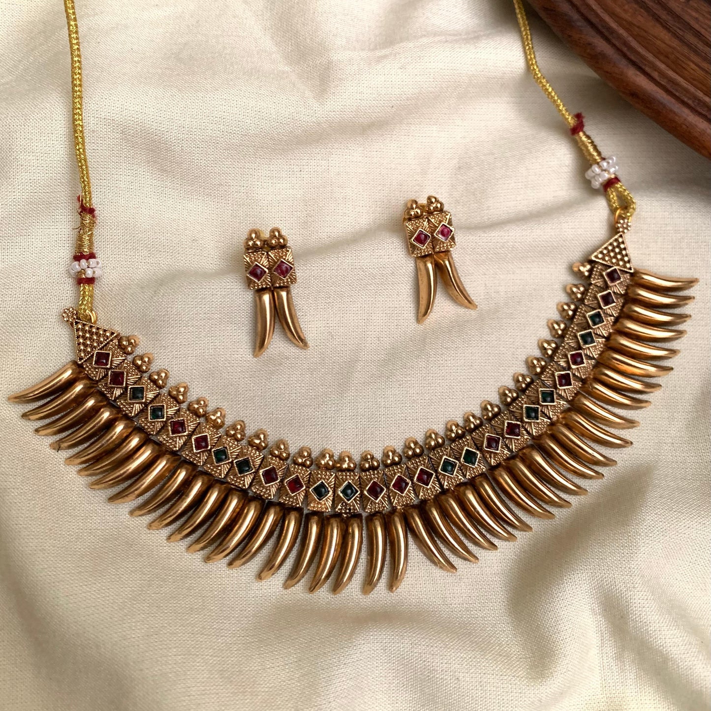 Gold necklace and earrings on a beige fabric background