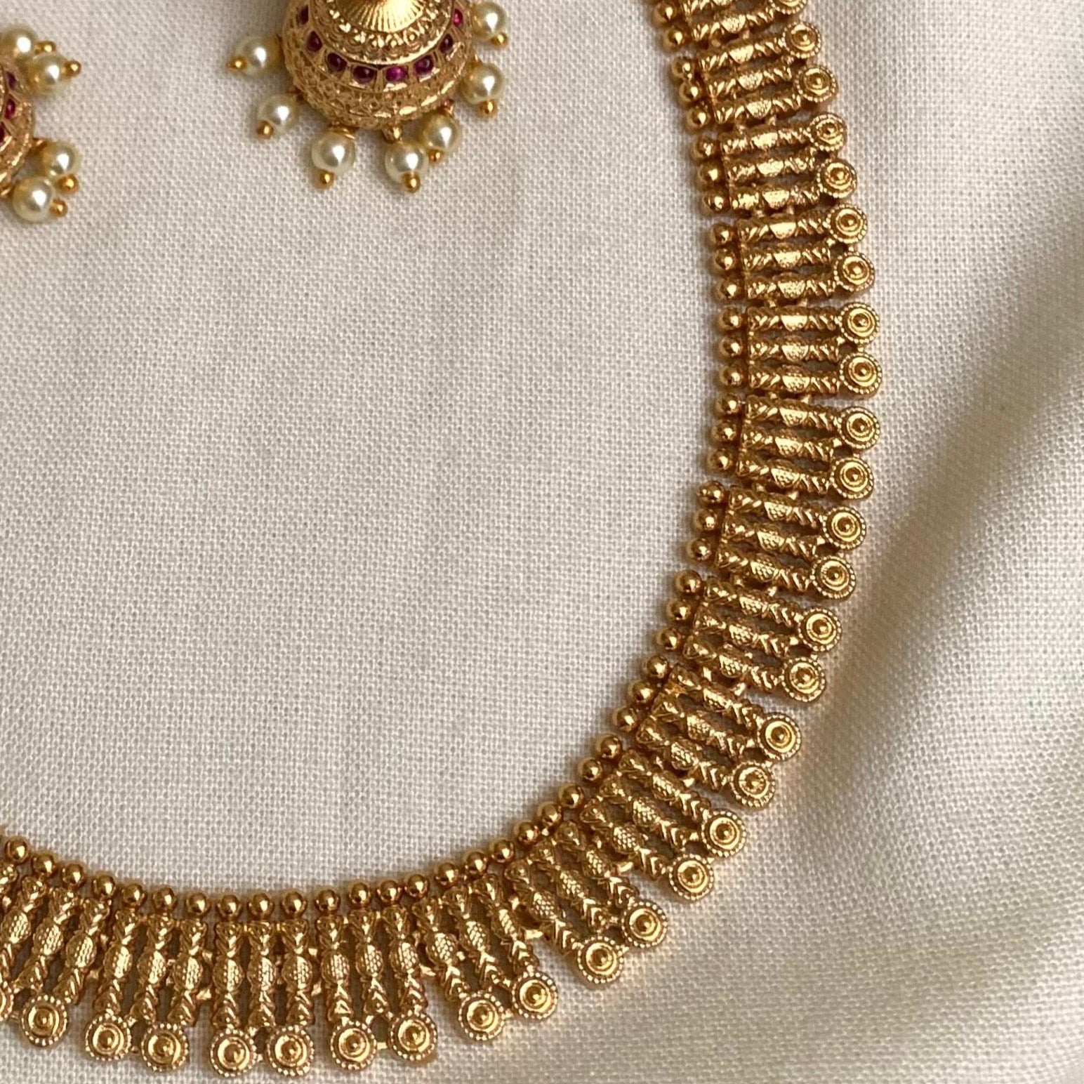 Gold necklace and earrings on a light fabric background