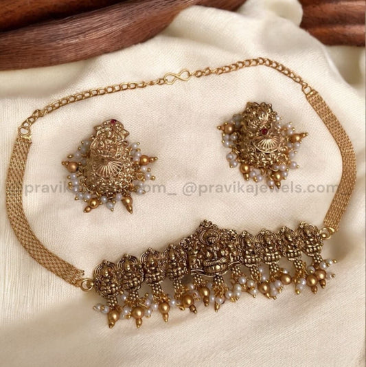 Gold jewelry set with necklace and earrings on a white fabric background
