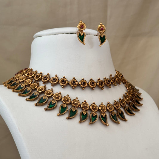 Gold necklace with green stones and matching earrings on a mannequin bust.