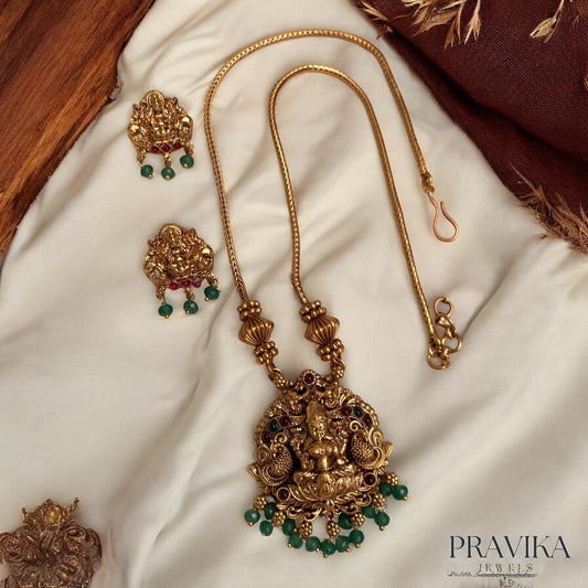 Gold necklace with green beads on a white fabric background, branded 'PRAVIKA'.