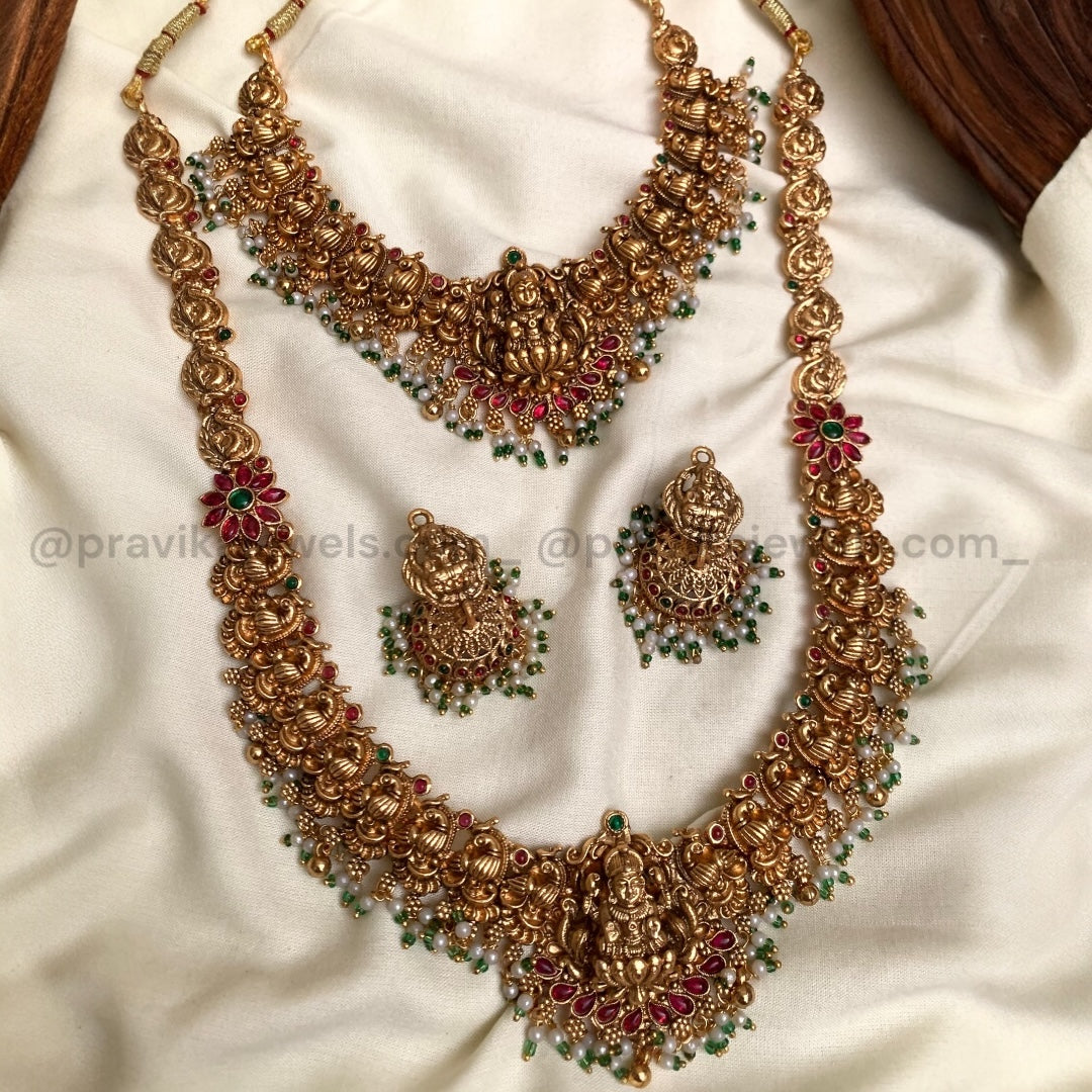 Gold necklace and earrings set on a white fabric background