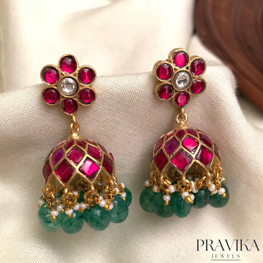 Gold and gemstone earrings with Pravika Jewels branding on a light background