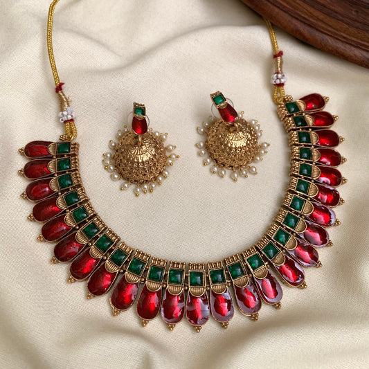 Ornate necklace with red and green gemstones on a beige fabric background