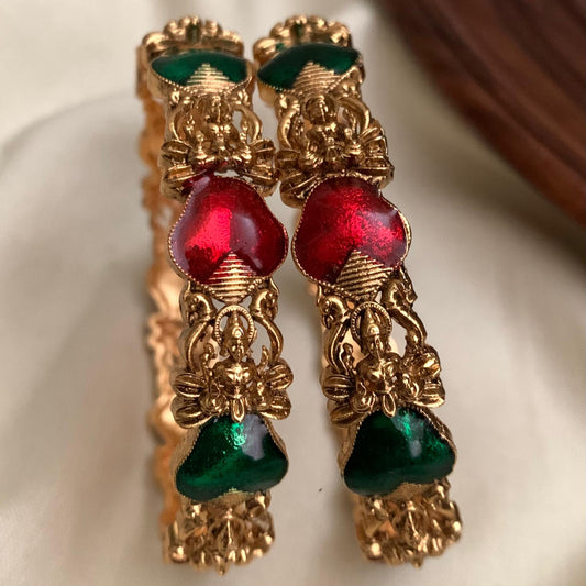 Gold earrings with red and green gemstones on a white background