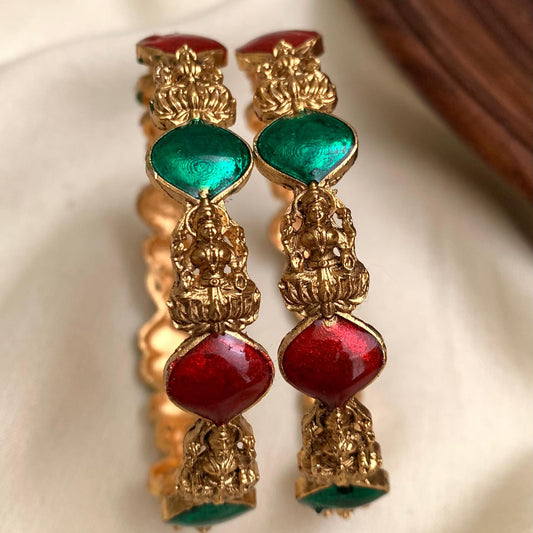 Gold earrings with red and green gemstones on a white background