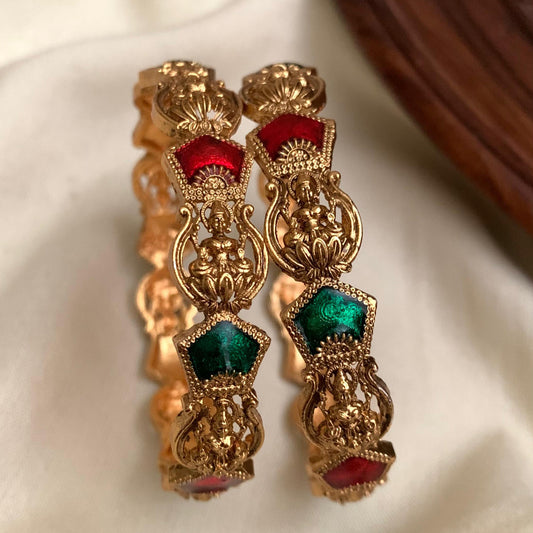 Gold earrings with red and green gemstones on a white background