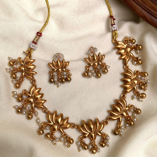 Gold necklace and earrings set on a beige fabric background