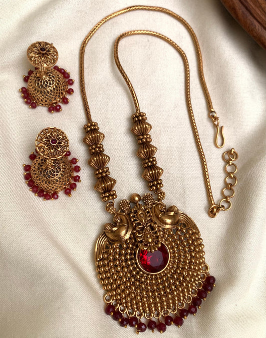 Gold necklace with red stones on a beige fabric background