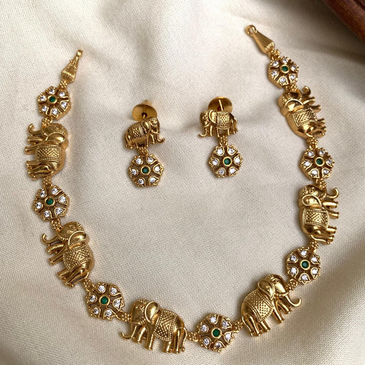 Gold elephant-themed jewelry set on a beige fabric background
