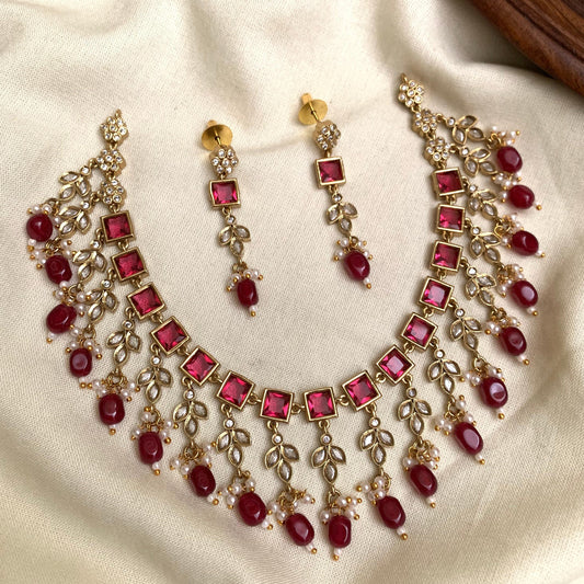 Necklace and earrings set with red gemstones on a beige fabric background