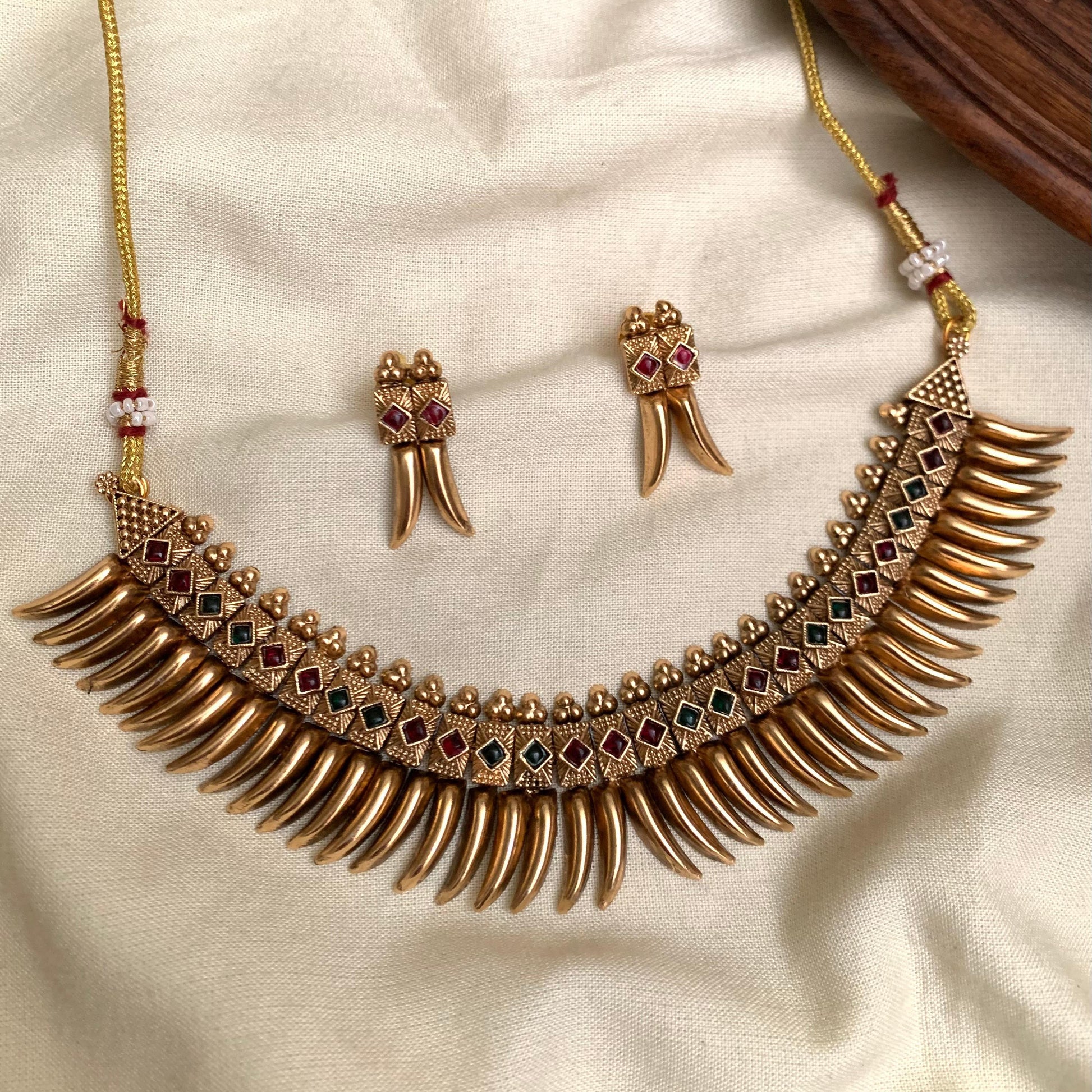 Gold necklace and earrings on a beige fabric background