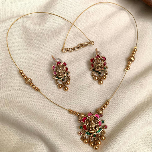 Gold necklace with floral design and red gemstones on a beige fabric background