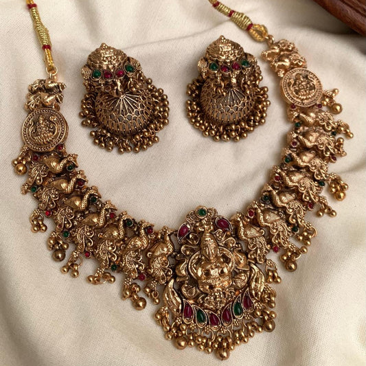 Ornate gold necklace and earrings on a white fabric background