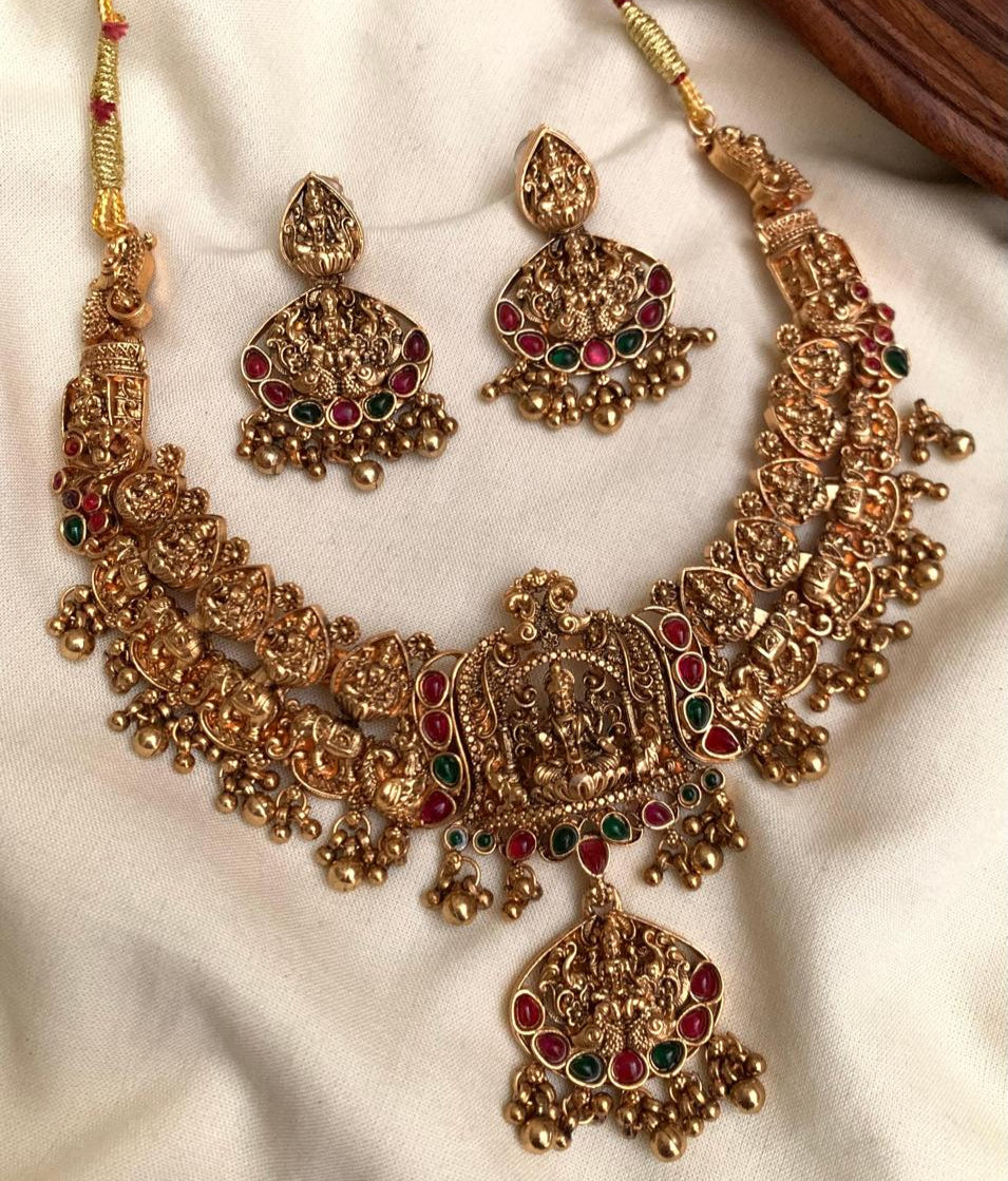 Gold jewelry set with necklace, earrings, and hair accessories on a white fabric background