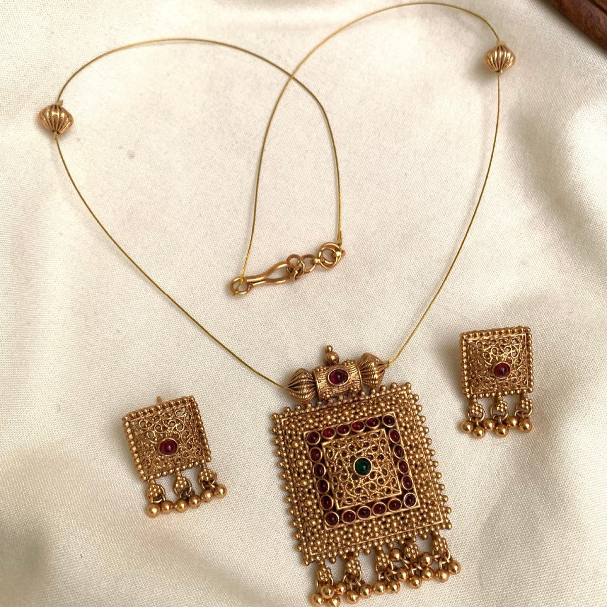 Gold necklace and earrings set on a white fabric background