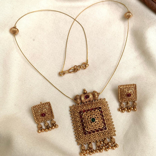Gold necklace and earrings set on a white fabric background