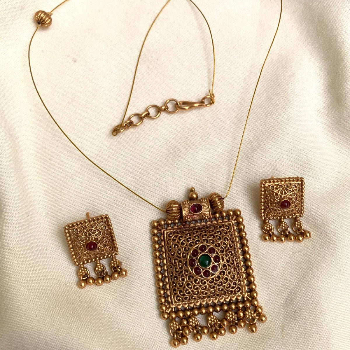 Gold necklace and earrings set on a white fabric background