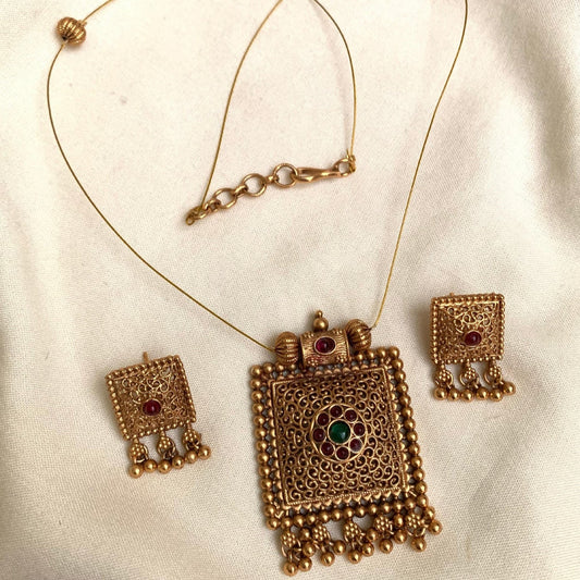 Gold necklace and earrings set on a white fabric background