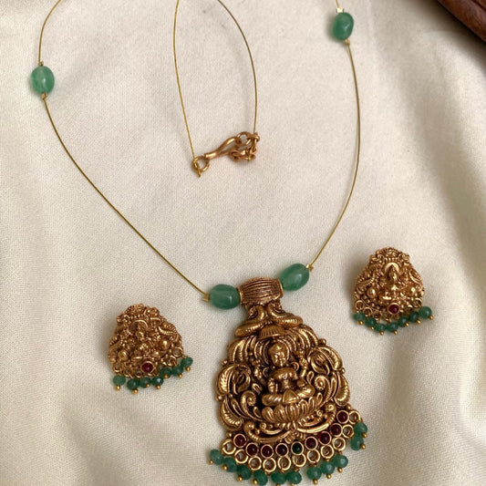 Gold necklace with green beads on a white fabric background