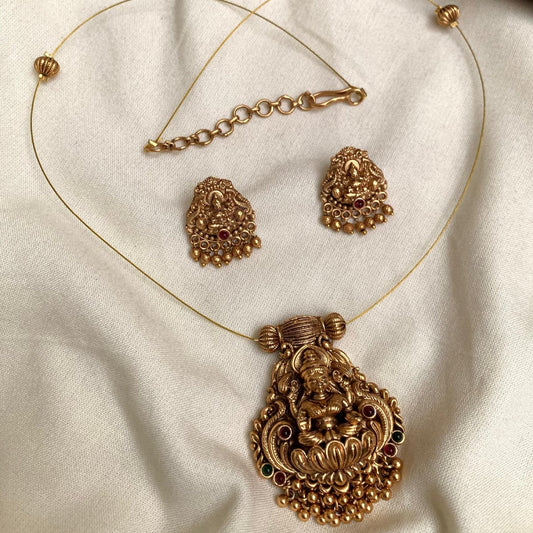 Gold necklace and earrings on a beige fabric background
