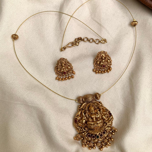 Gold necklace and earrings set on a beige fabric background
