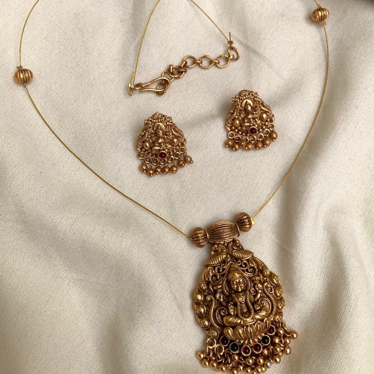 Gold necklace and earrings on a beige fabric background