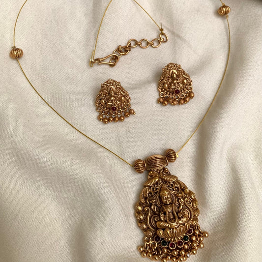Gold necklace and earrings on a beige fabric background